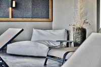 Modern ausgestatteter Ruheraum mit einem Gro&szlig;en grauen Sitzkissen im Deluxe Apartment n&auml;he des Blindsees