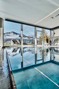 Ganzj&auml;hrig beheizter Indoor-Infinity Pool mit Liegebereich und Aussicht auf die Berge